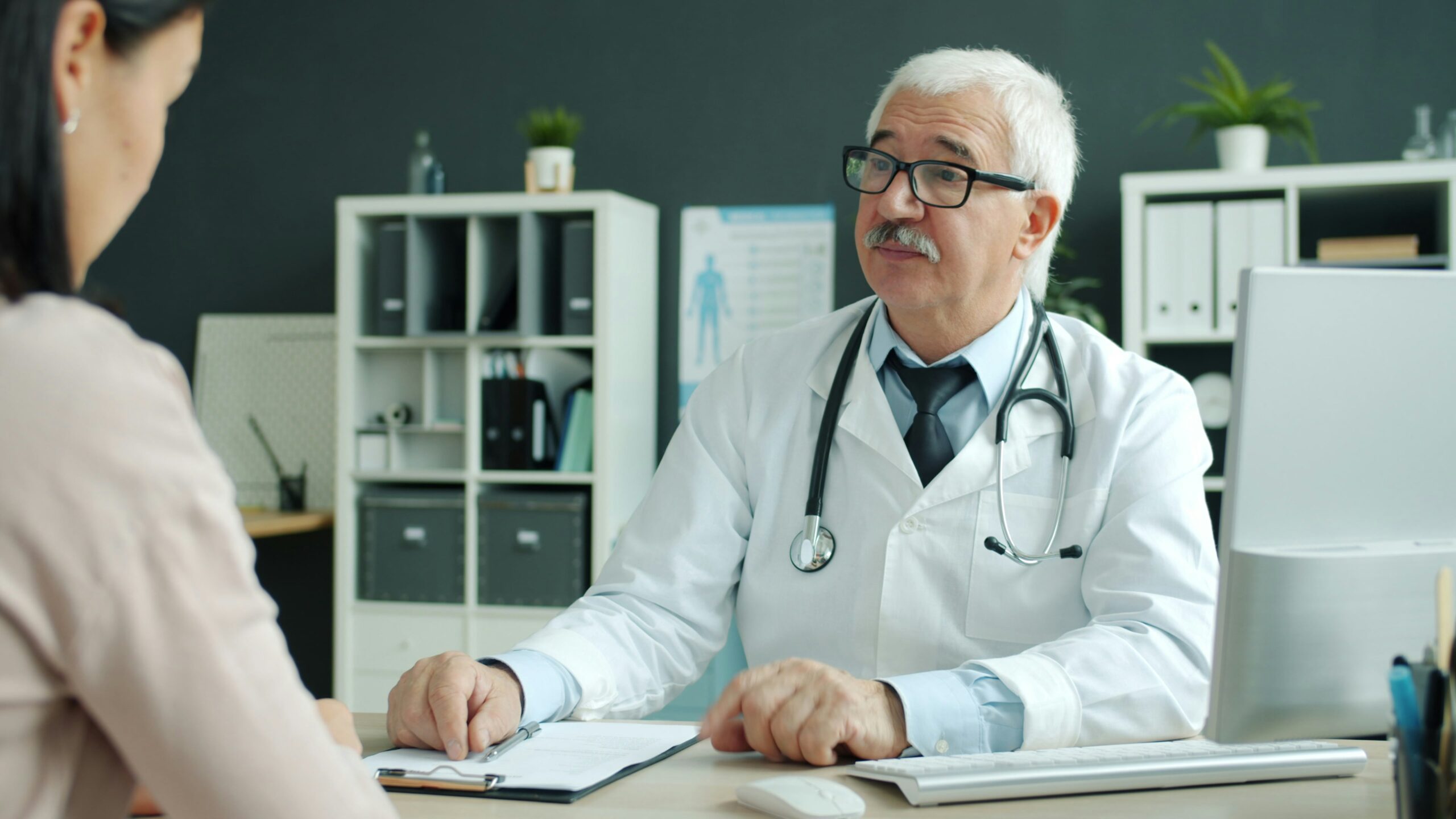 A doctor and patient shaking hands and talking at a desk during an appointment, representing the trust an affirming provider relationship should feel like