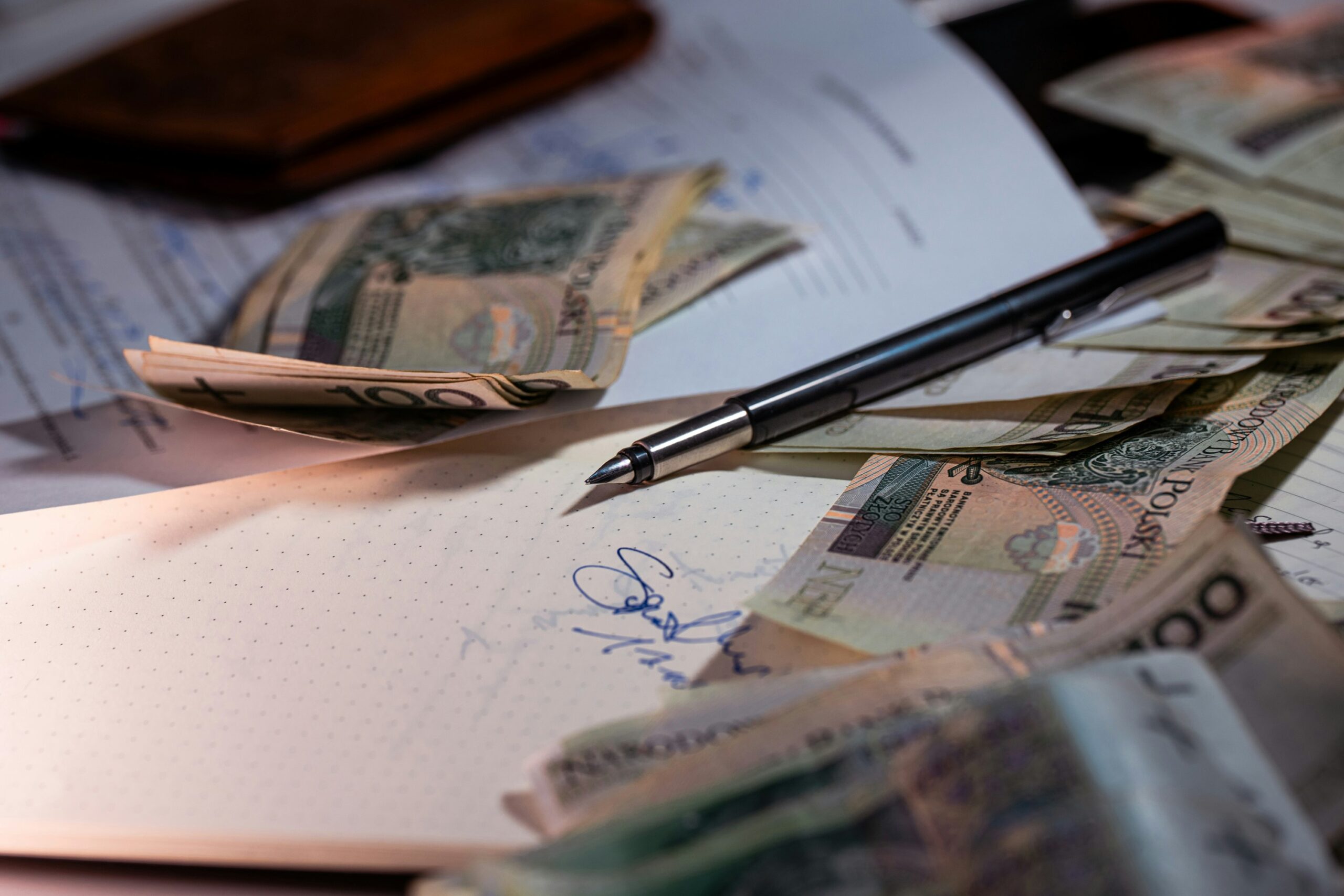 A pen and money scattered across paperwork, representing the real cost of navigating healthcare expenses