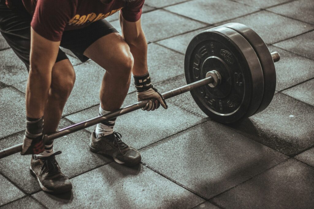 A person mid-lift with a barbell in a gym, representing informed, careful strength training for every body