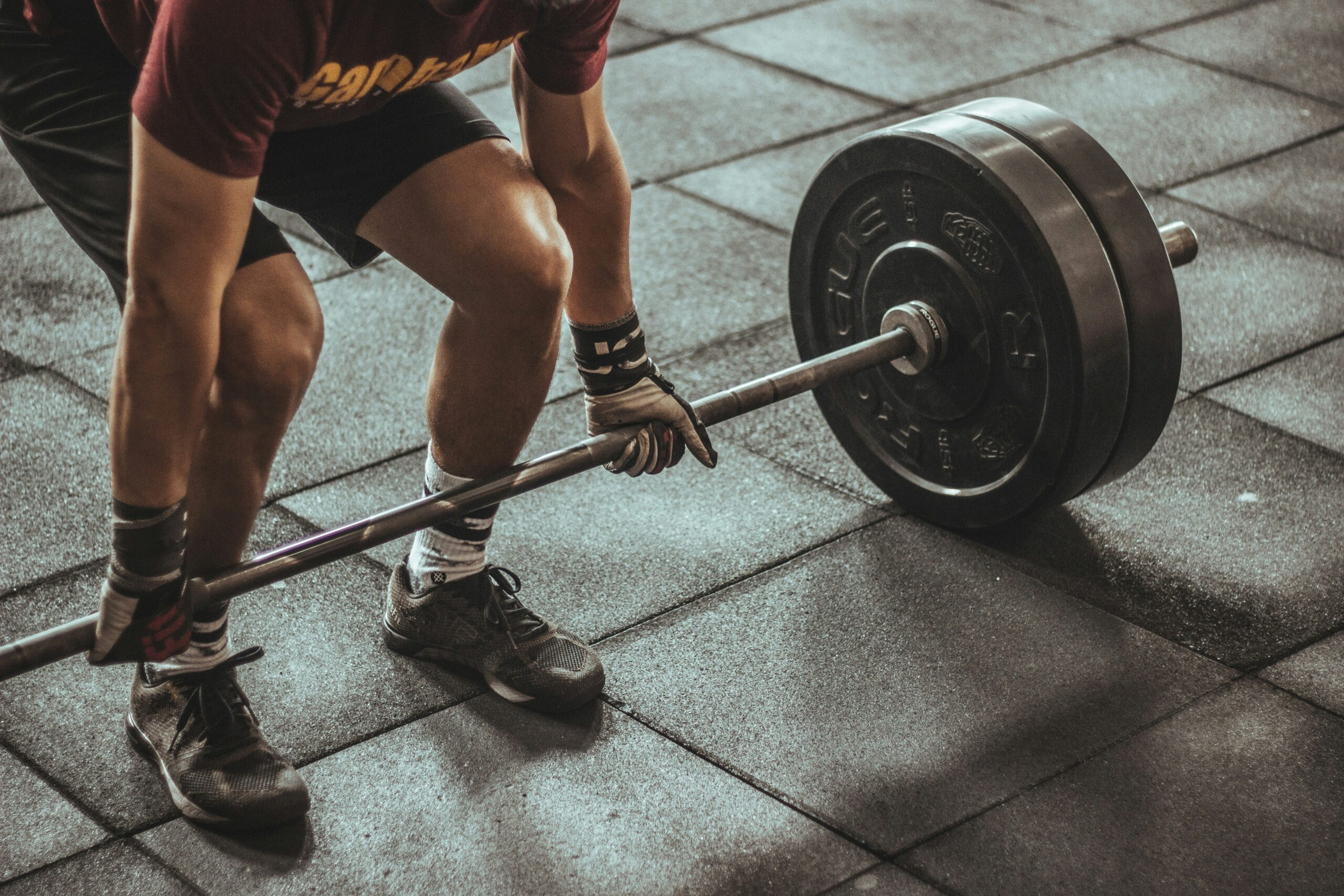 A person mid-lift with a barbell in a gym, representing informed, careful strength training for every body