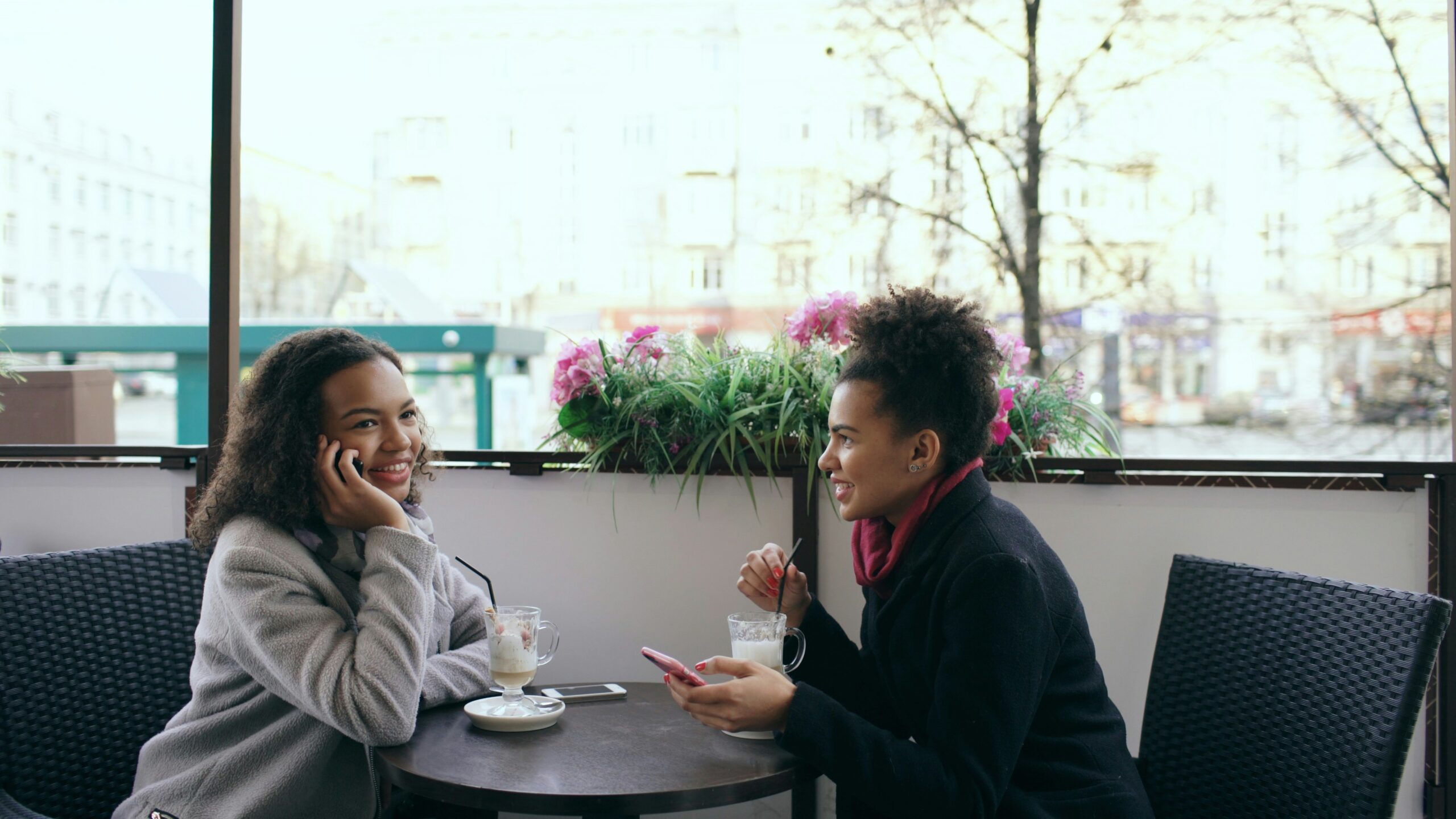 Two people talking closely at an outdoor cafe table, representing the steady, human-scale support that matters most when the legal news feels overwhelming